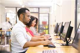 Diverse group of students taking online tests in computer class.